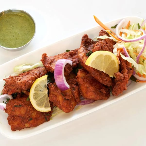 Abhiruchi Grill's Chicken 65, a spicy Indian fried chicken dish, with lemon, onion, and green chutney.