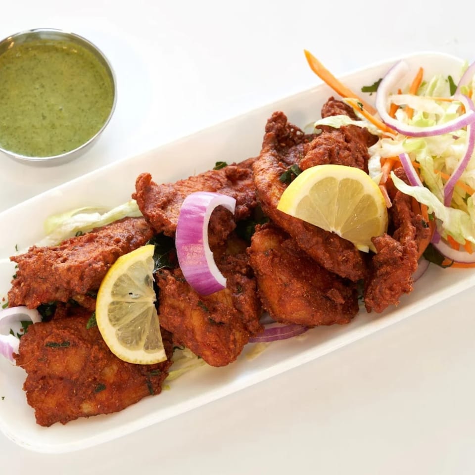 Abhiruchi Grill's Chicken 65, a spicy Indian fried chicken dish, with lemon, onion, and green chutney.