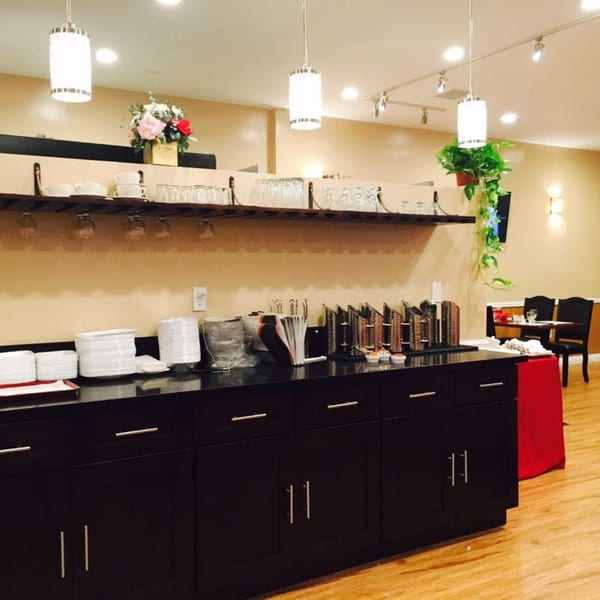 Abhiruchi Grill's buffet area with chafing dishes, plates, glasses, and floral decor.